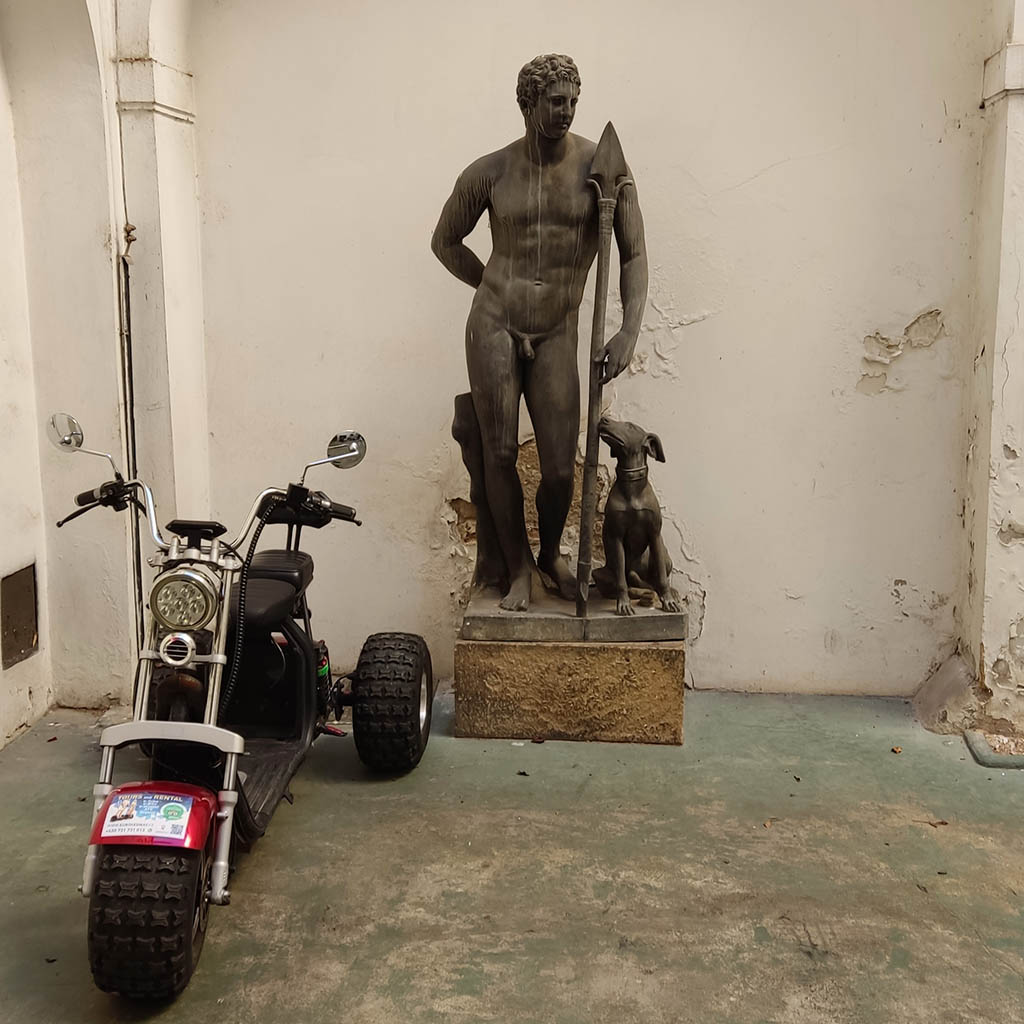 Adventure Trike geparkt neben einer Statue in einem Prager Innenhof