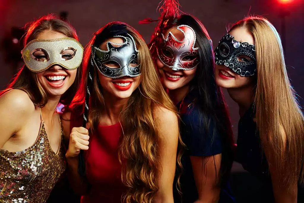Group of happy girls in masquerade masks having party
